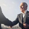 man in black suit shaking hands with another man
